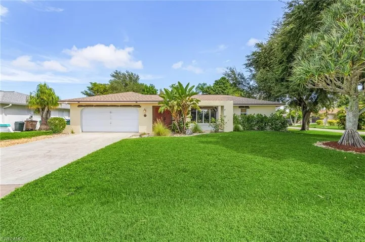 Single story home with a garage and a front lawn