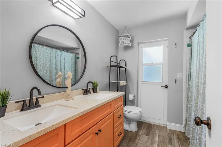 Bathroom with vanity, toilet, a shower with curtain, and hardwood / wood-style floors