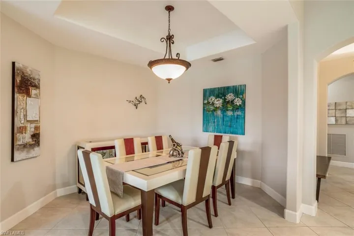 Dining area featuring a raised ceiling, light tile patterned floors, and arched walkways