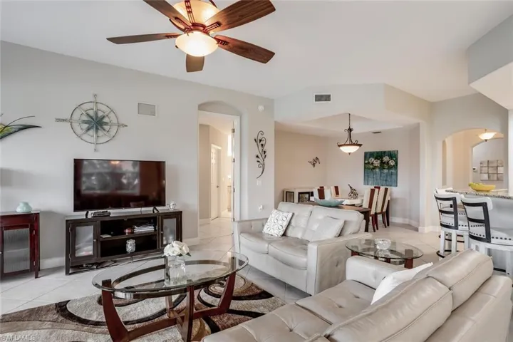 Tiled living room featuring arched walkways and ceiling fan