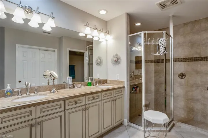 Full bathroom featuring double vanity, a shower stall, light tile patterned flooring, and recessed lighting