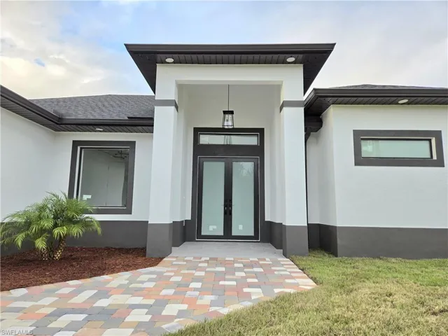 View of exterior entry with french doors and a yard
