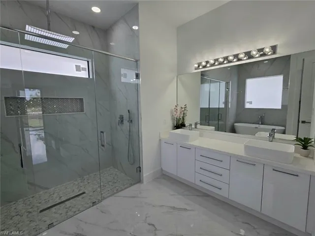 Bathroom with vanity, shower with separate bathtub, and a wealth of natural light