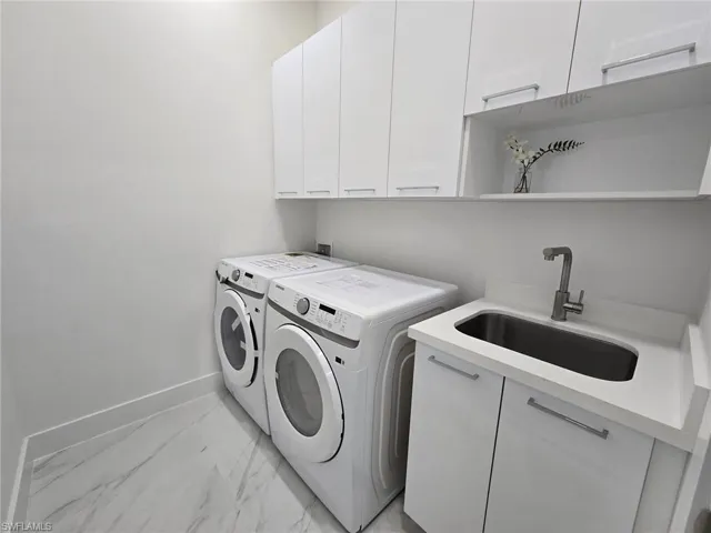 Laundry room featuring cabinets, washer and dryer, and sink