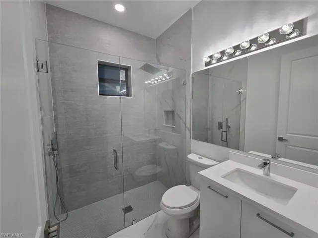 Bathroom featuring toilet, walk in shower, and vanity
