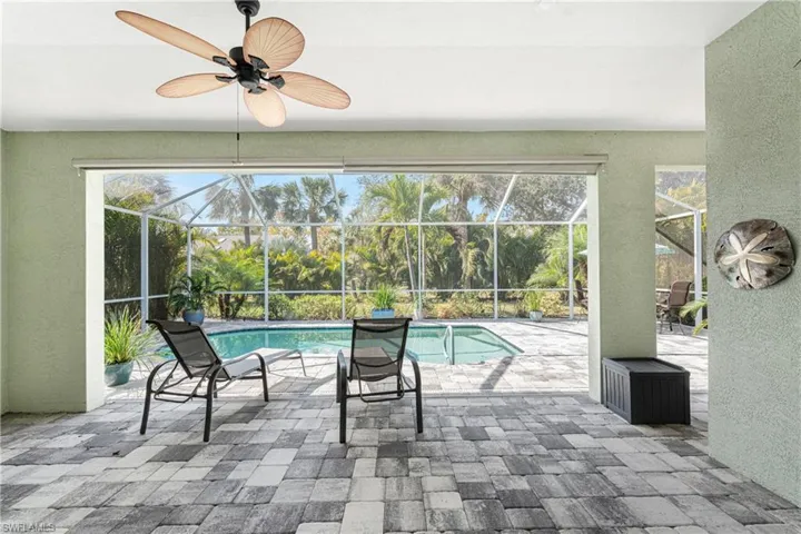 View of swimming pool with ceiling fan, glass enclosure, and a patio area