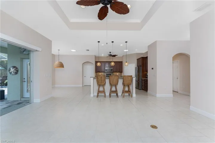 Kitchen with appliances with stainless steel finishes, decorative light fixtures, and a raised ceiling
