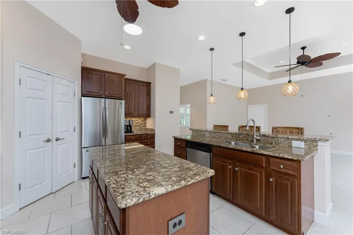 Kitchen featuring a kitchen island with sink, sink, decorative light fixtures, and appliances with stainless steel finishes