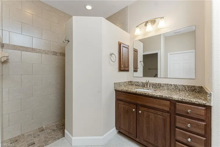 Bathroom with tiled shower, vanity, and tile patterned flooring