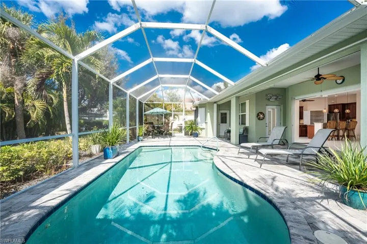 View of swimming pool featuring a patio, ceiling fan, and glass enclosure