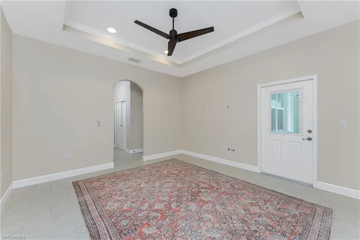 Spare room featuring light tile patterned floors, ornamental molding, a raised ceiling, and ceiling fan