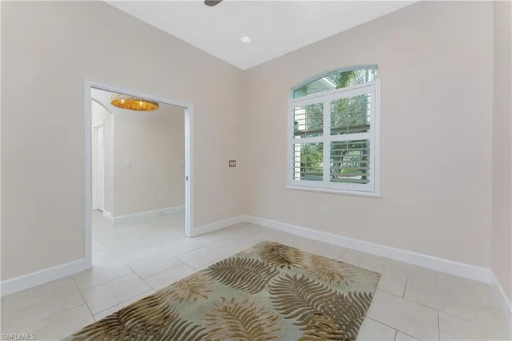 Tiled den/office room featuring arched windows and plantation shutters