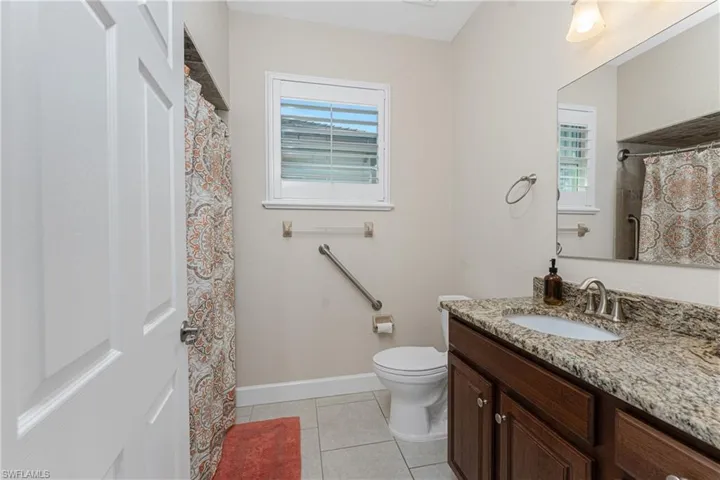 Bathroom featuring vanity, a wealth of natural light, tile patterned floors, and toilet