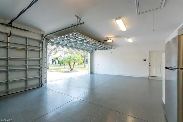 Garage featuring a garage door opener and stainless steel fridge
