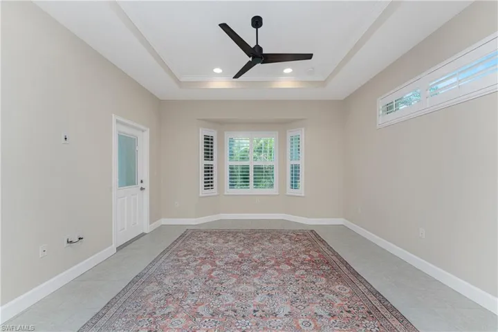 Tiled spare room with ceiling fan, a tray ceiling, ornamental molding, and a healthy amount of sunlight