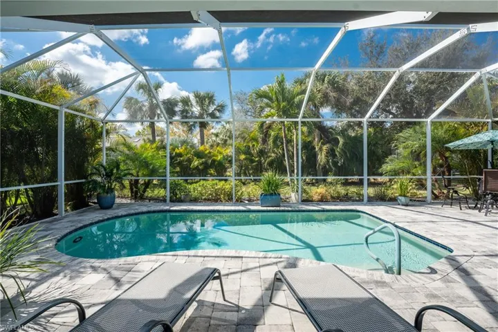 View of pool with a patio and glass enclosure