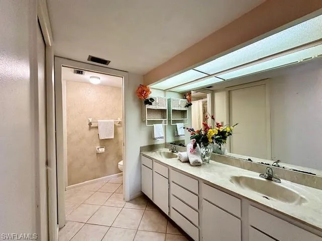 Bathroom featuring toilet, vanity, and tile patterned flooring