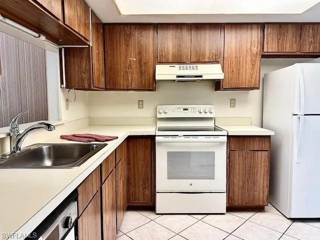 Kitchen with white appliances, sink, and light tile patterned floors