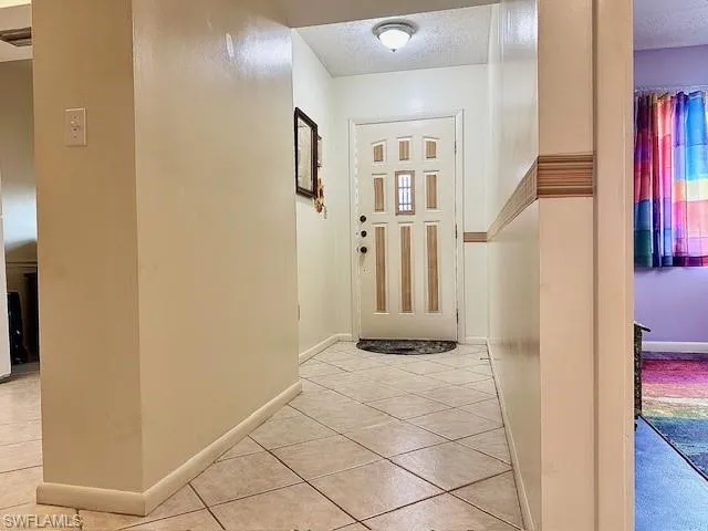 Corridor with a textured ceiling and light tile patterned floors