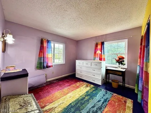 Bedroom with multiple windows and a textured ceiling