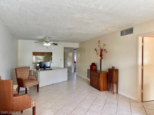 Tiled living room with a textured ceiling and ceiling fan