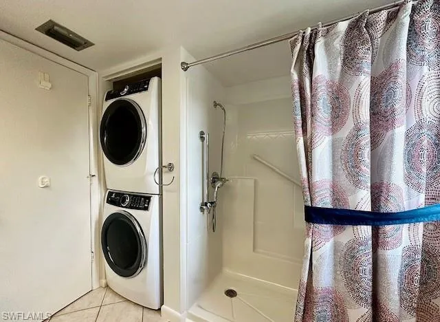 Washroom featuring stacked washing maching and dryer and light tile patterned floors
