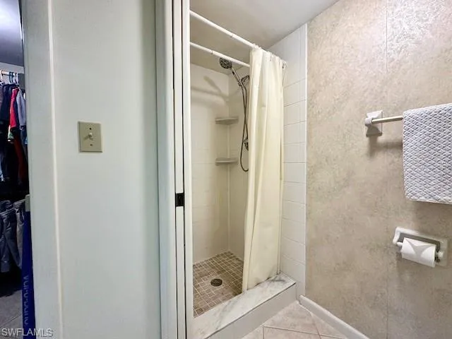 Bathroom with a shower with curtain and tile patterned flooring