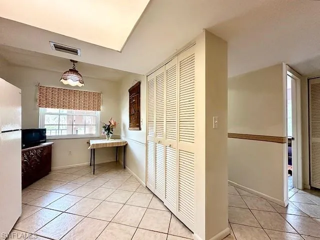 Kitchen featuring light tile patterned flooring, white fridge, and decorative light fixtures