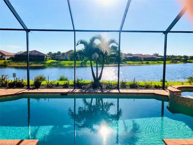 View of pool featuring glass enclosure, a sunroom, a pool with connected hot tub, and a residential view