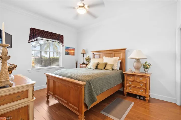 Bedroom featuring hardwood / wood-style floors, ornamental molding, and a ceiling fan