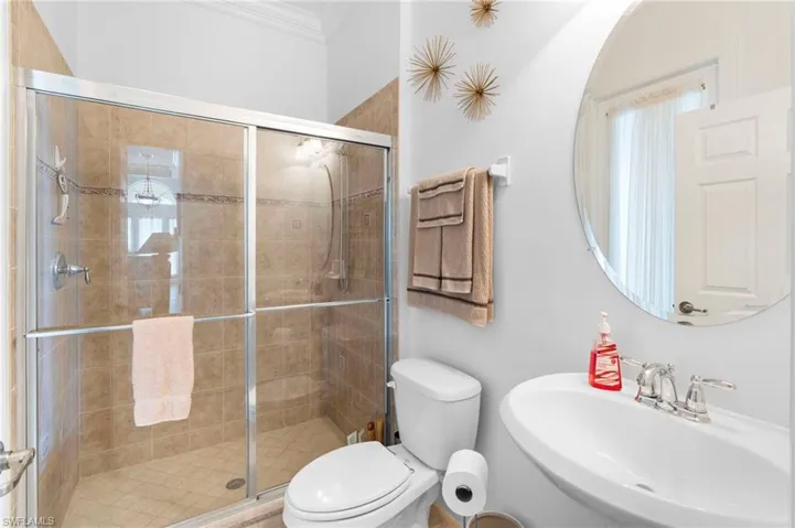 Bathroom featuring a shower stall and crown molding