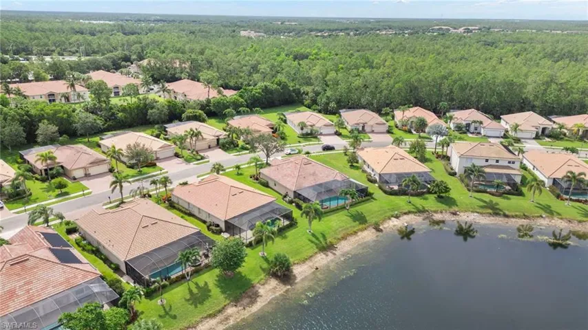 Aerial view of residential area with a heavily wooded area and a nearby body of water