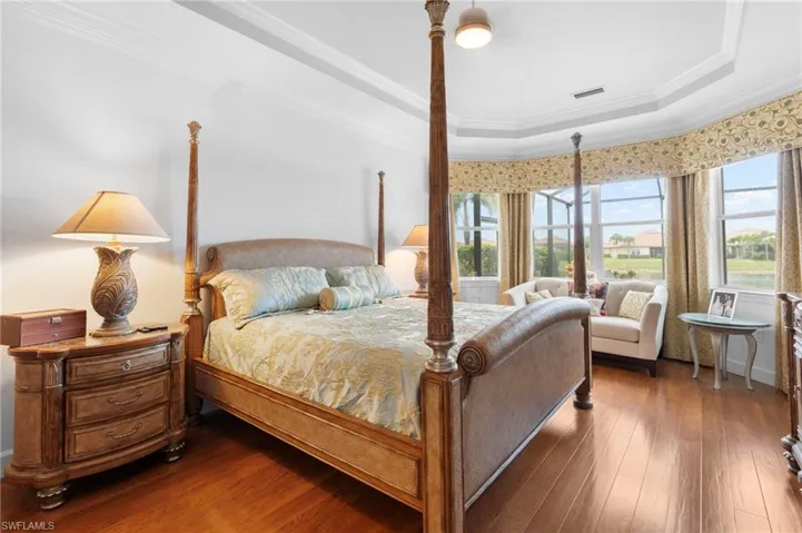 Bedroom featuring ornamental molding, dark wood-type flooring, and a raised ceiling