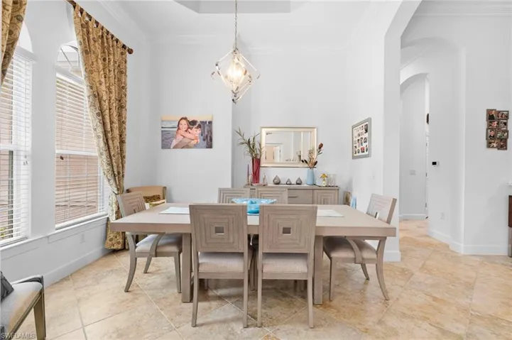 Dining room featuring arched walkways, crown molding, a chandelier, and a towering ceiling
