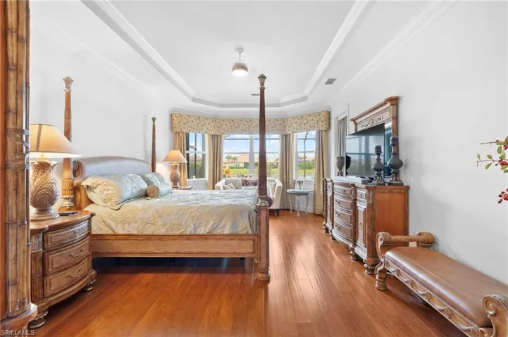 Bedroom with a raised ceiling, hardwood / wood-style flooring, and crown molding