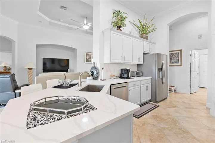 Kitchen with arched walkways, ornamental molding, white cabinets, open floor plan, and stainless steel appliances