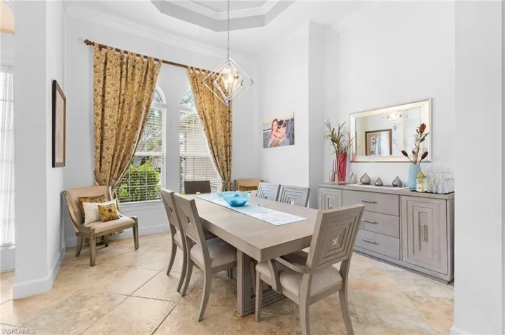 Dining area with ornamental molding, a raised ceiling, and a chandelier