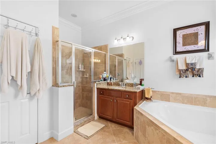 Bathroom with a bath, crown molding, a stall shower, vanity, and light tile patterned floors