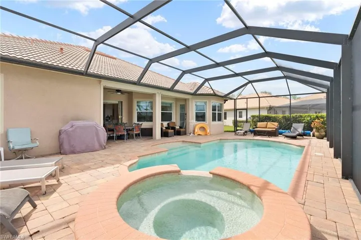 View of swimming pool with an outdoor living space, a pool with connected hot tub, glass enclosure, and a sunroom