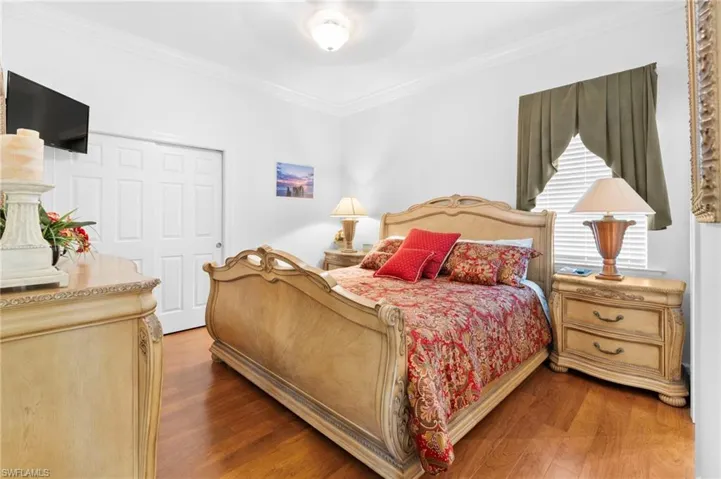 Bedroom with crown molding, wood finished floors, a closet, and a ceiling fan