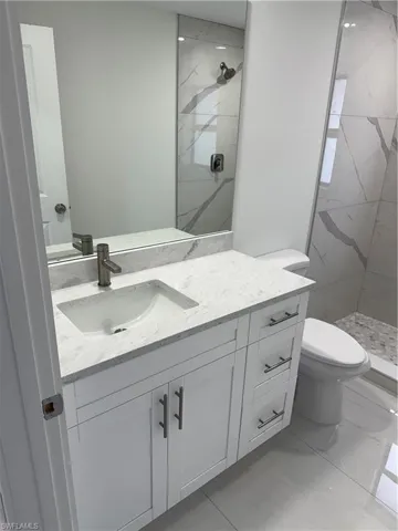 Bathroom featuring toilet, a tile shower, and vanity