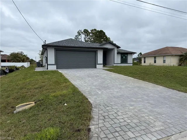 View of front facade featuring a garage, a front lawn, and central AC unit