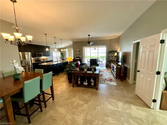 Dining space featuring lofted ceiling, sink, and ceiling fan with notable chandelier