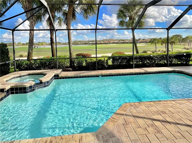 View of swimming pool featuring glass enclosure and an in ground hot tub