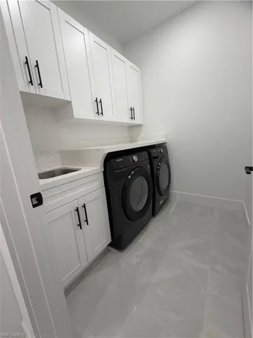 Laundry area featuring separate washer and dryer and cabinet space
