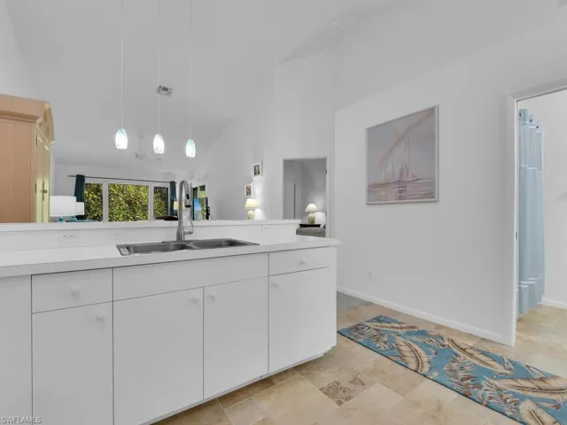 Kitchen featuring white cabinets, pendant lighting, sink, and high vaulted ceiling