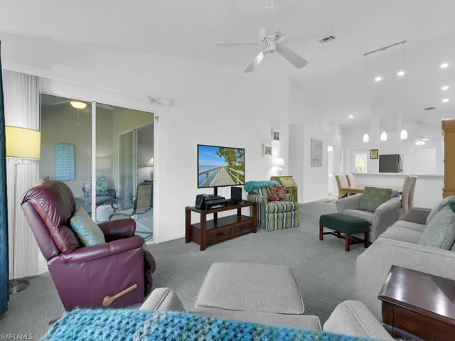 Carpeted living room with ceiling fan and high vaulted ceiling