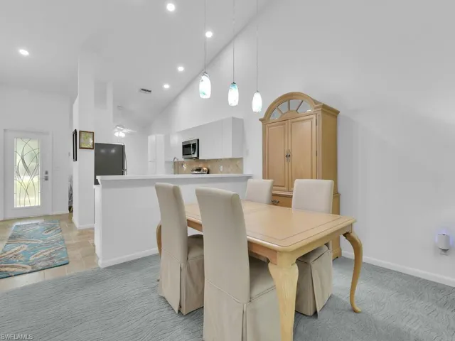 Dining room with light carpet, high vaulted ceiling, and ceiling fan