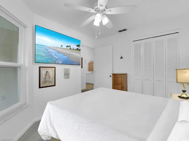 Carpeted bedroom with ceiling fan and a closet