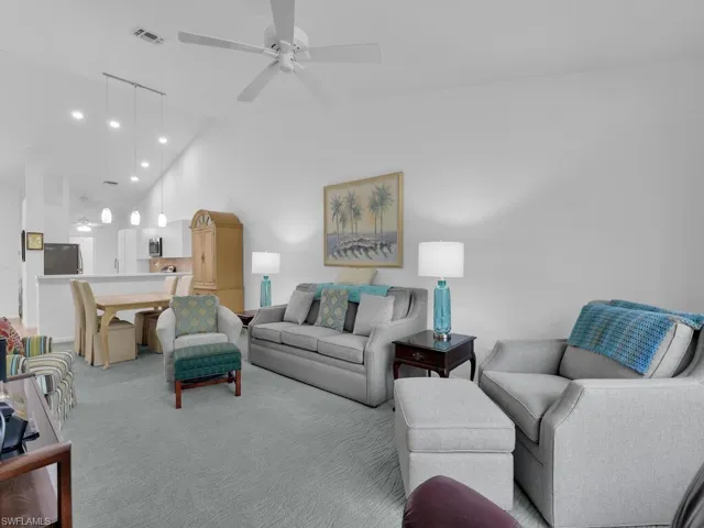 Carpeted living room with ceiling fan and high vaulted ceiling